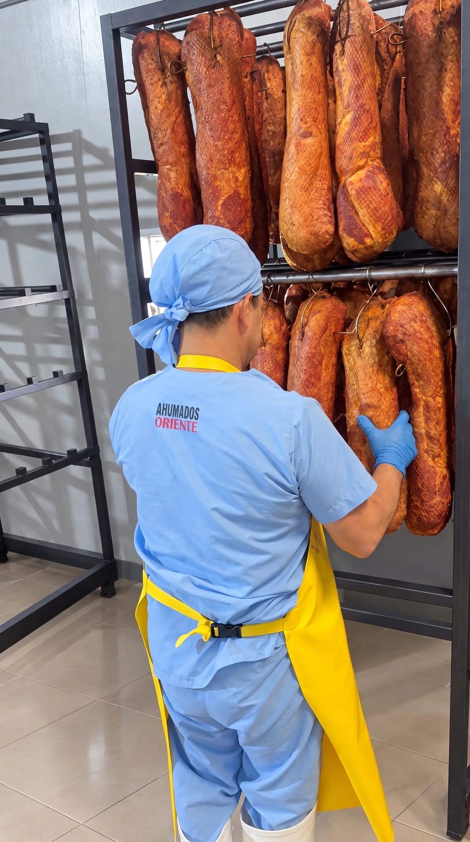 Un operario de Ahumados Oriente revisando piezas ahumadas colgadas en la planta